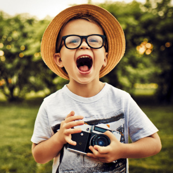 Jumping, hyperactive little boy in white shirt against white background